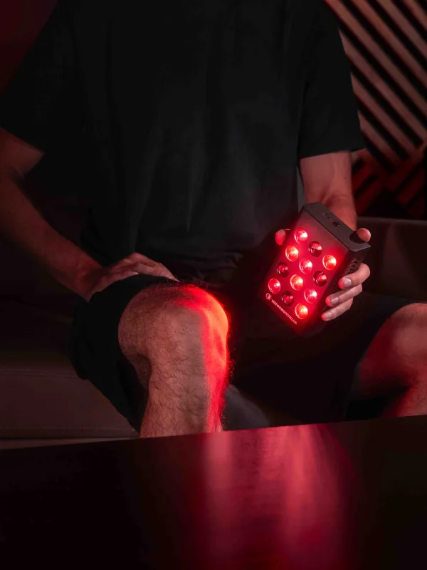 Mitochondriak® mini Panel in der Hand am Knie, RED- und NIR-Licht